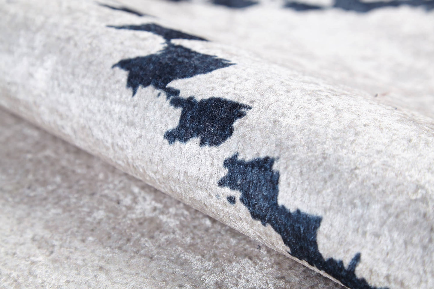 Close-up of the Moroccan Mosaic - Washable Rug - JR1655 in light gray-anthracite, featuring a soft, textured surface and abstract dark blue and black patterns; shown partially rolled to display its plush material—ideal for high-traffic areas.