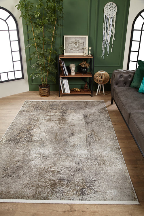 Load image 1 in gallery view. A modern living room with the Noble Insignia - Washable Rug - JR1830 in textured gray—ideal for allergy-sensitive or high-traffic homes—features a gray tufted sofa, green cushions, small art bookshelf, tall plant, dreamcatcher, and arched windows.
