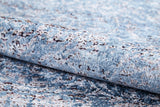 A close-up of the Old World Charm - Washable Rug - JR1606, rolled up to show its blue and gray stone-like abstract texture—ideal for high-traffic areas.