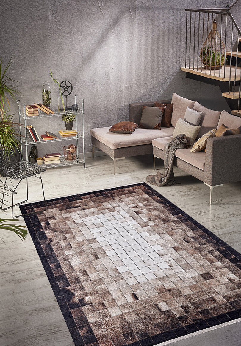 A modern living room with a gray sectional sofa, brown and beige cushions, the Pinstripe Paradise - Washable Rug - JR1004 in gray and brown geometric patterns, a metal decor shelf, indoor plants, and a staircase with wood steps and metal railing.