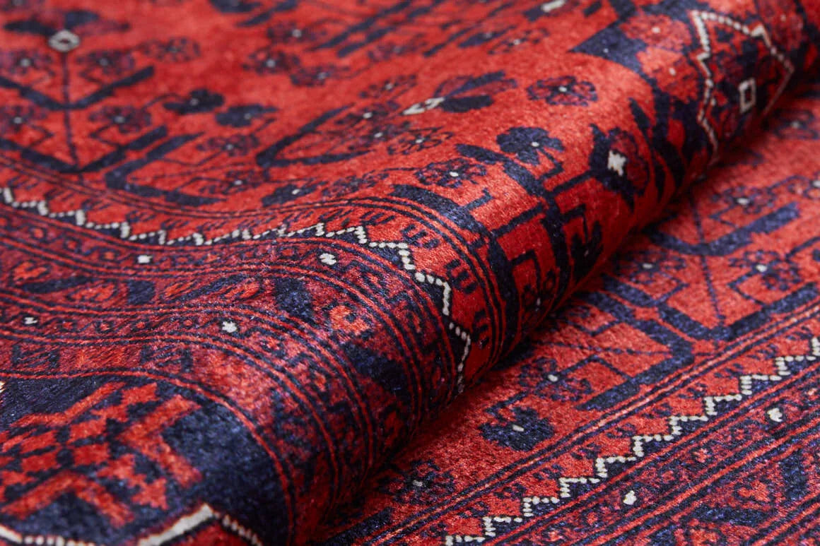 Close-up of the Regal Accents - Washable Rug - JR36: a traditional Persian-style red rug featuring intricate geometric patterns in deep red, dark blue, and black, detailed borders and motifs, with fabric slightly folded—ideal for high-traffic areas.