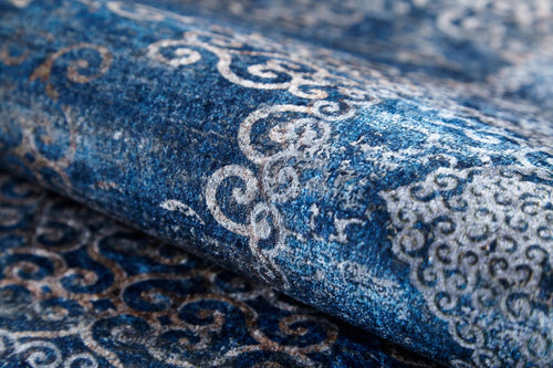 Load image 1 in gallery view. A close-up of the Regal Insignia - Washable Rug - JR1786 reveals rich texture and detailed blue, white, and beige swirling patterns—an ideal choice for high-traffic areas.