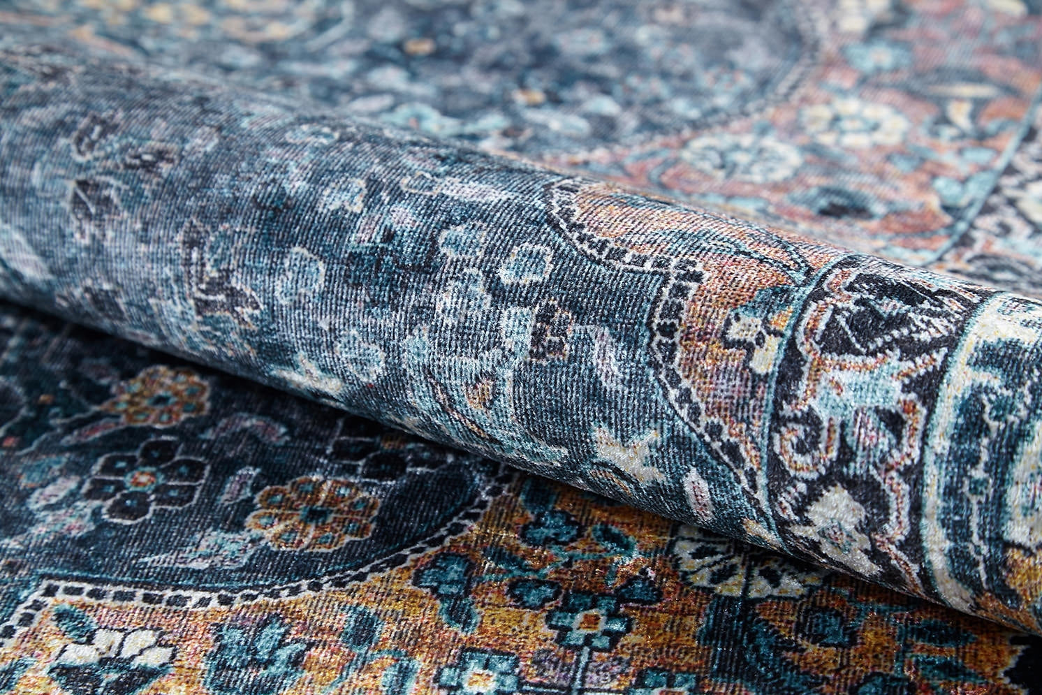 A close-up of the Royal Sultan - Washable Rug - JR1970, rolled up to reveal its detailed floral and geometric patterns in blue, teal, yellow, and orange—perfect for allergy-sensitive homes with its easy-to-clean design.