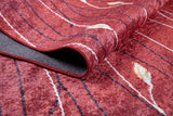 A close-up of the Secret Garden - Washable Rug - JR1656 in red, featuring curved black lines and white and yellow leaf shapes, with a folded corner showing the underside—ideal for busy, high-traffic spaces.