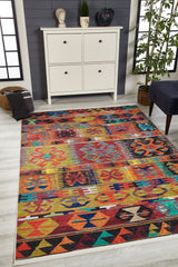 The Serene Sahara - Washable Rug - JR1959, with its vibrant geometric patterns, brightens the light wood floor. Perfect for high-traffic areas, it sits by a white cabinet with decor, a potted plant, and a dark cushion in an airy, sunlit room.