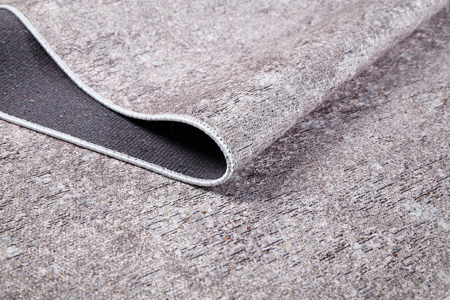 A close-up of the Slate Charm - Washable Rug (JR1740) shows its cream and beige, stone-textured pattern with dark backing and stitched edge—durable, washable, and ideal for high-traffic areas.