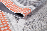 A close-up of the Sleek Design - Washable Rug - JR1727 shows orange and black geometric patterns on a light background with a folded corner revealing its texture—perfect for allergy-sensitive, high-traffic areas.