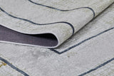 A close-up of the Sleek and Contemporary - Washable Rug - JR1365 in gray with dark geometric lines; its folded corner reveals texture and thickness—perfect for allergy-sensitive homes.