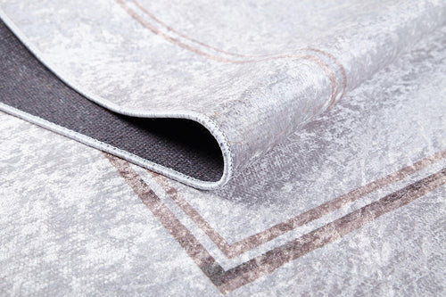 Load image 1 in gallery view. A close-up of the Sophisticated Edging - Washable Rug - JR1738 shows its light gray flat weave with a subtle brown border. One corner is folded to reveal the black non-slip backing—a practical, stylish choice for any space.