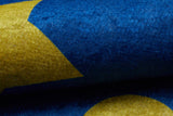 A close-up of the Starry Dreams - Machine-Washable Rug JRC004 shows its allergy-friendly, velvety blue surface with bold yellow geometric shapes like a partial star and circle. Vivid colors and textured details enhance its visual appeal.