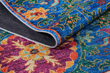 A close-up of the Summer Bouquet - Washable Rug - JR1358 showcases vibrant blue, red, yellow, and orange floral patterns. A folded corner reveals its detailed washable texture—ideal for high-traffic areas.