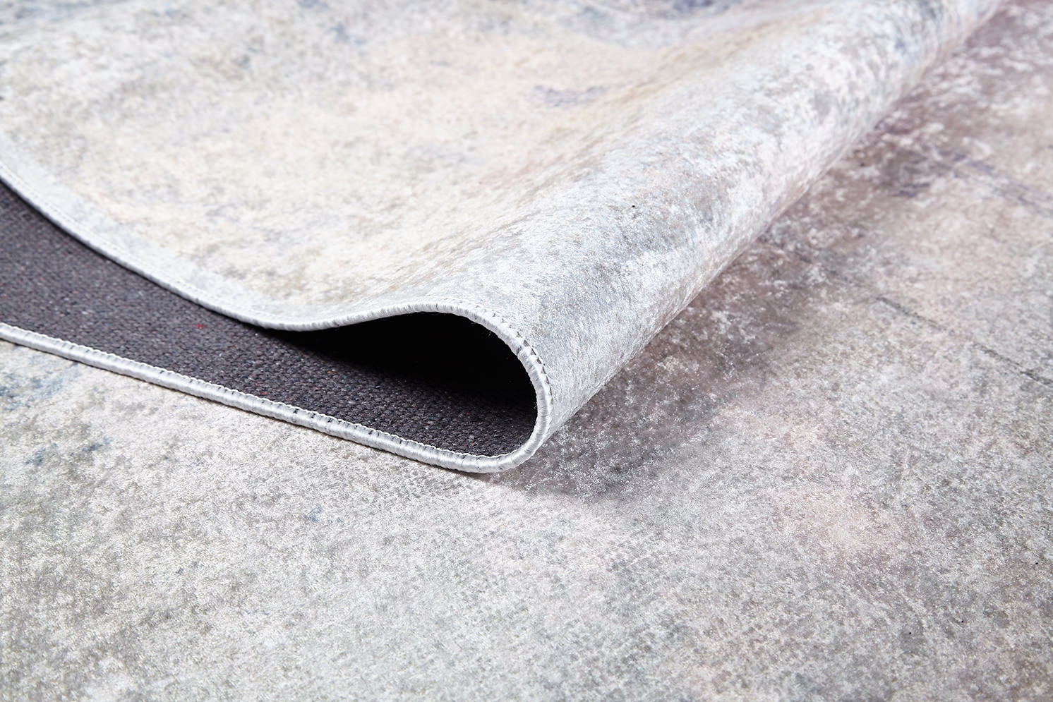 Close-up of the Sunset Sky Ombre - Washable Rug (JR1918) in light gray-anthracite, showcasing its marbled pattern, stitched border, and underside—perfect as a washable rug for high-traffic spaces.