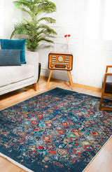 A living room features a white sofa, blue cushions, a vintage radio on a wooden stand, a potted plant, and the Tarnished Elegance - Washable Rug - JR1095—perfect for high-traffic areas—on a wooden floor with sunlight streaming in.