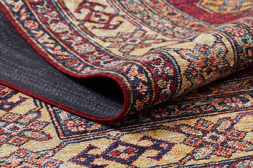 Load image 1 in gallery view. A close-up of the Time-Honored Textures - Washable Rug - JR40 shows its rolled edge, revealing detailed floral and geometric patterns in red, gold, blue, and cream. The visible backing highlights its durability—ideal for high-traffic areas.