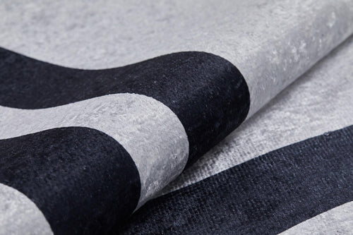 Load image 1 in gallery view. Close-up of the Timeless Border - Washable Rug - JR572 in gray-anthracite, featuring thick black and light gray curved stripes. The partially rolled rug highlights its smooth, soft texture and bold modern design.