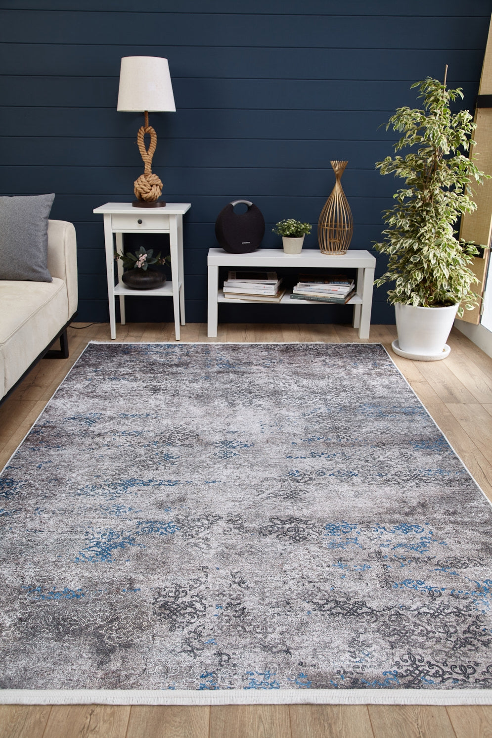 Modern living room with a Timeless Embellishment - Washable Rug - JR1943 in gray, white side tables, lamp, decor, books, potted plant, beige sofa, and navy blue accent wall.