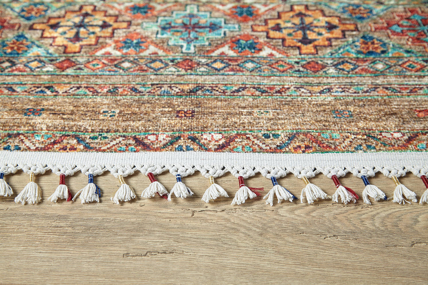 The Tribal Tango - Washable Rug - JR5089 features intricate geometric patterns in red, blue, and tan with a decorative white fringe accented in red and blue—ideal for high-traffic areas on light wood floors.