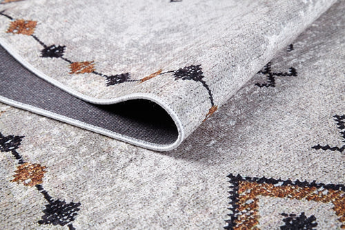Load image 1 in gallery view. A close-up of the Tribal Tassel - Washable Rug - JR1683, featuring cream and beige with black and brown geometric patterns, its corner folded to show a dark gray backing—ideal for high-traffic areas.