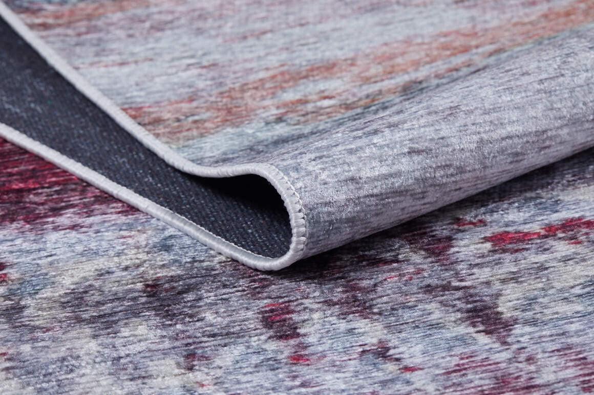 A close-up of the Vintage Brushed - Washable Rug - JR143 in grey, red, and purple shades shows one corner lifted to display the underside and edge stitching.
