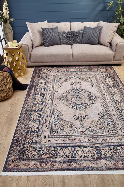 Load image 1 in gallery view. A living room with a beige sofa, grey and fur pillows, candles on a decorative side table, a basket with a blanket, plants, and the Vintage Charm - Washable Rug - JR1933 for high-traffic areas on wood floors. The wall behind is dark blue.
