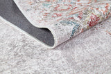 A close-up of the Vintage Cream - Machine-Washable Rug (JR5006) flipped over on a light gray textured floor, highlighting its woven underside and colorful topside design.