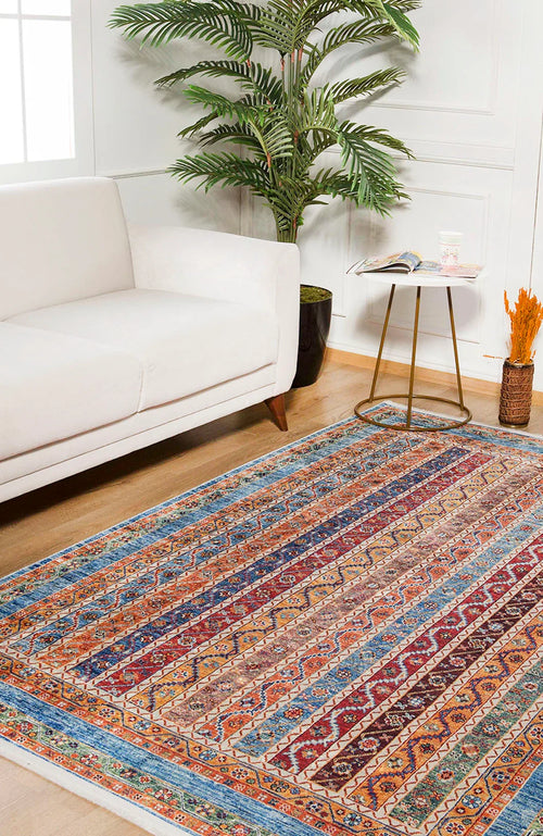 Load image 1 in gallery view. The Vintage Vibes - Washable Rug - JR37, featuring multicolor geometric designs, brightens the wood floor beside a white sofa, round gold side table with books, and a tall potted plant—ideal for high-traffic modern living rooms.
