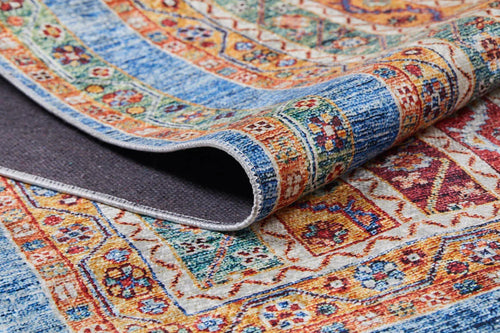Load image 1 in gallery view. A close-up of the Vintage Vibes - Washable Rug - JR37, featuring intricate blue, red, yellow, and orange geometric and floral patterns. One corner is lifted to show the underside—ideal for stylish durability in high-traffic areas.