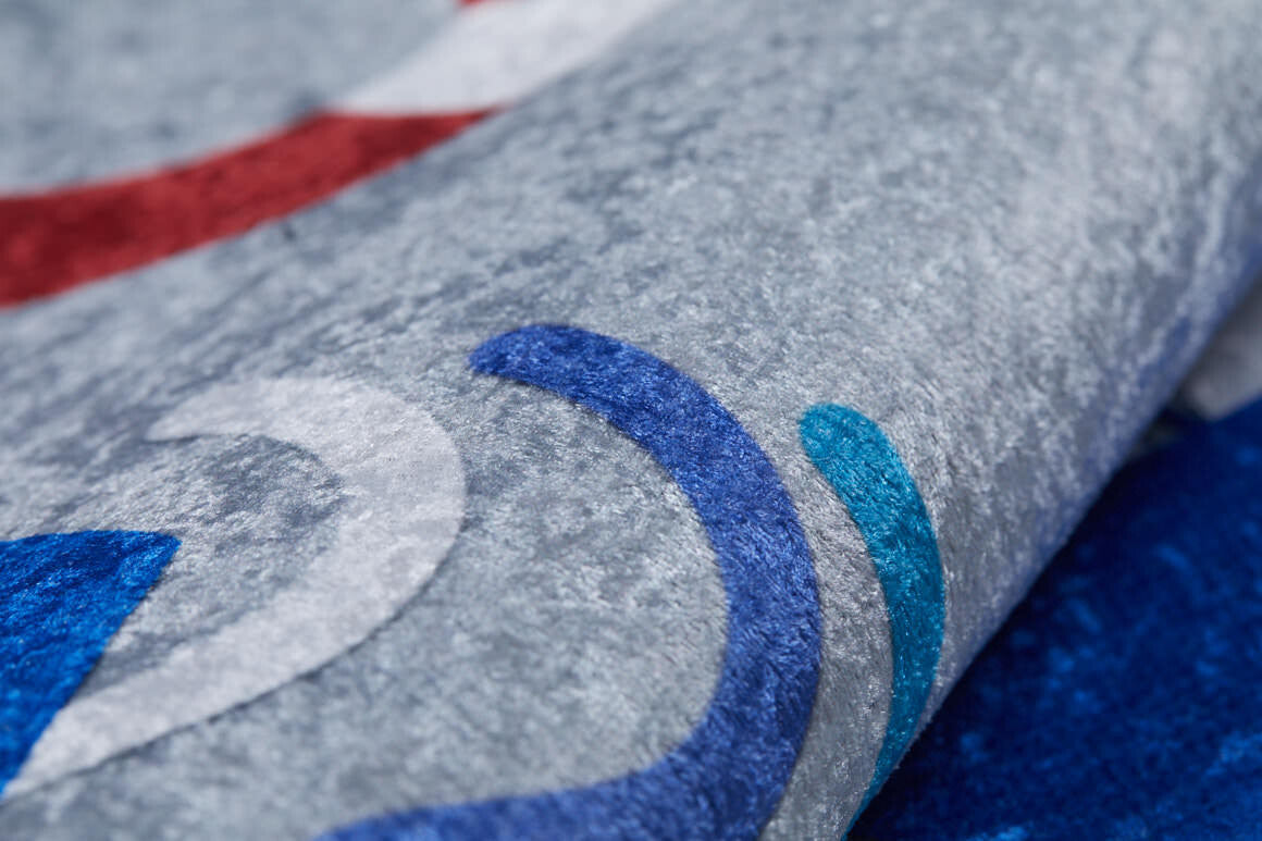 A close-up of the WaveVenture - Machine-Washable Rug JRC087 in grey, featuring abstract curved patterns in blue, teal, white, and red. This soft, slightly shiny rug is perfect for high-traffic areas and easy to clean.