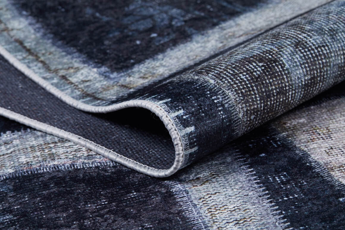 A close-up of the Windowpane Wonder - Washable Rug - JR184 shows its folded, textured flat weave with dark blue, gray, and white rectangles and visible edge stitching.