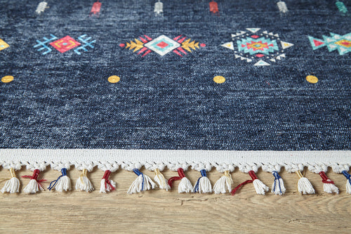 Load image 1 in gallery view. A close-up of the Wanderer's Way - Washable Rug - JR5101 in dark blue with colorful geometric patterns, yellow dots, and a white, red, and blue tasseled fringe—resting on wood flooring and ideal for high-traffic areas.